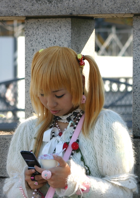 Harajuku girl checks her mobile phone
